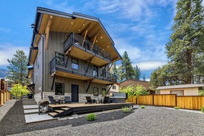 A modern two-story house with a balcony, outdoor seating, and a gravel driveway. - Stateline Designer Luxury Home (South Lake Tahoe)