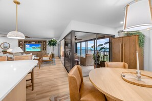 Ein modernes Wohnzimmer mit großem Fernseher, Holzmöbeln und Blick ins Freie.