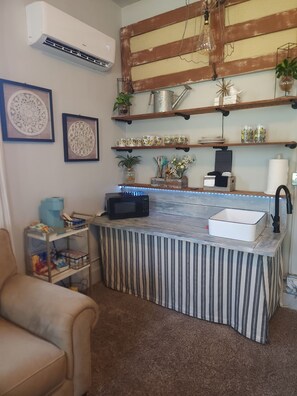 A kitchen with a striped countertop, a microwave, a sink, and shelves with decorative items.