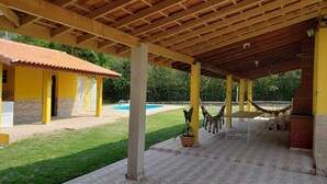 Ein überdachter Außenbereich mit Pool, gelbem Gebäude und Hängematte.