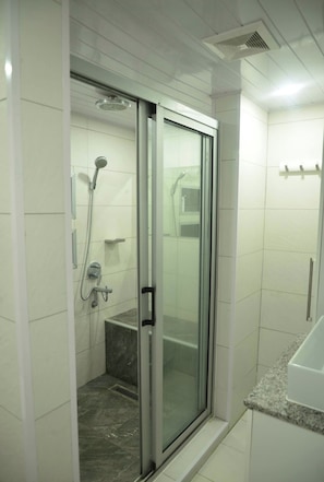 Ducha con puerta de vidrio, ducha de mano y toallero de pared.
