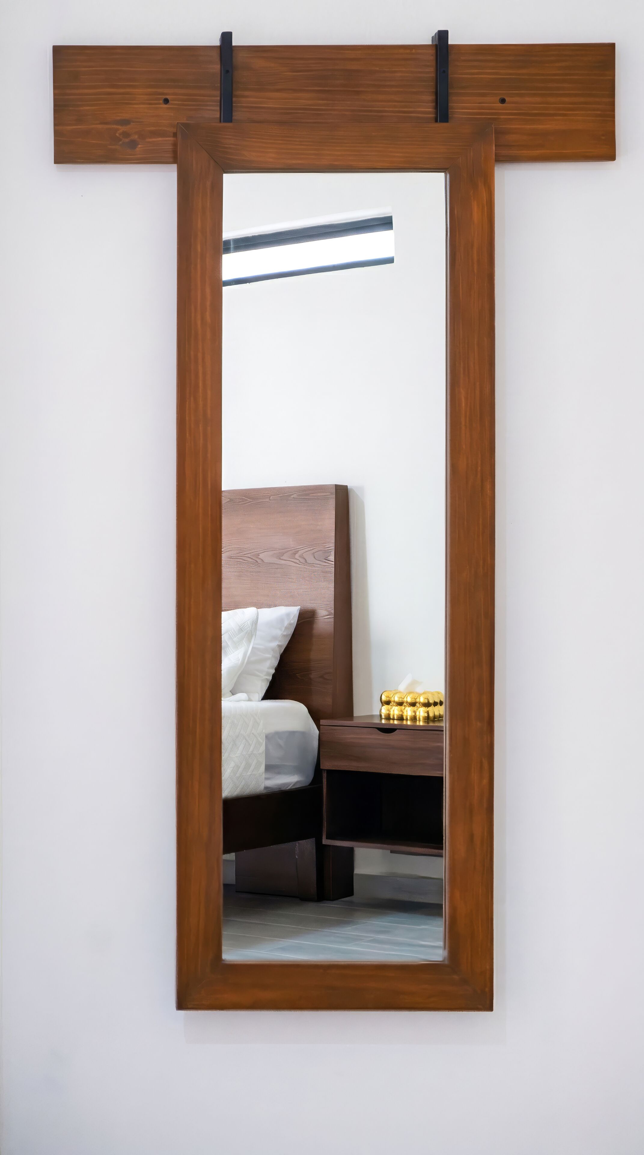 A bedroom with a bed, bedside table, and a mirror on the wall.