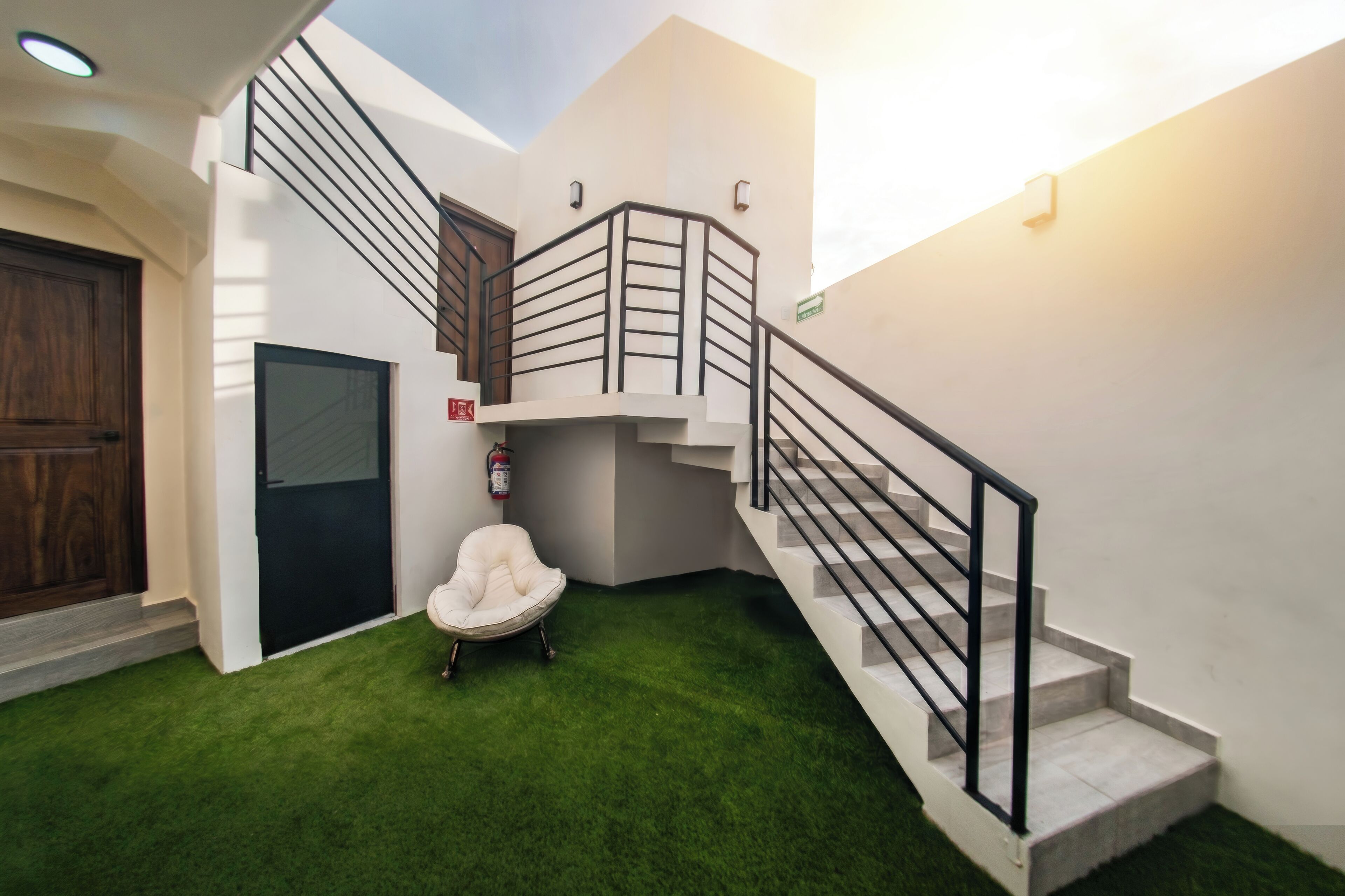 Un interior moderno con una escalera, una silla blanca y un extintor.