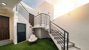 Un interior moderno con una escalera, una silla blanca y un extintor.