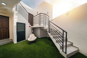 A modern interior with a staircase, a white chair, and a fire extinguisher.