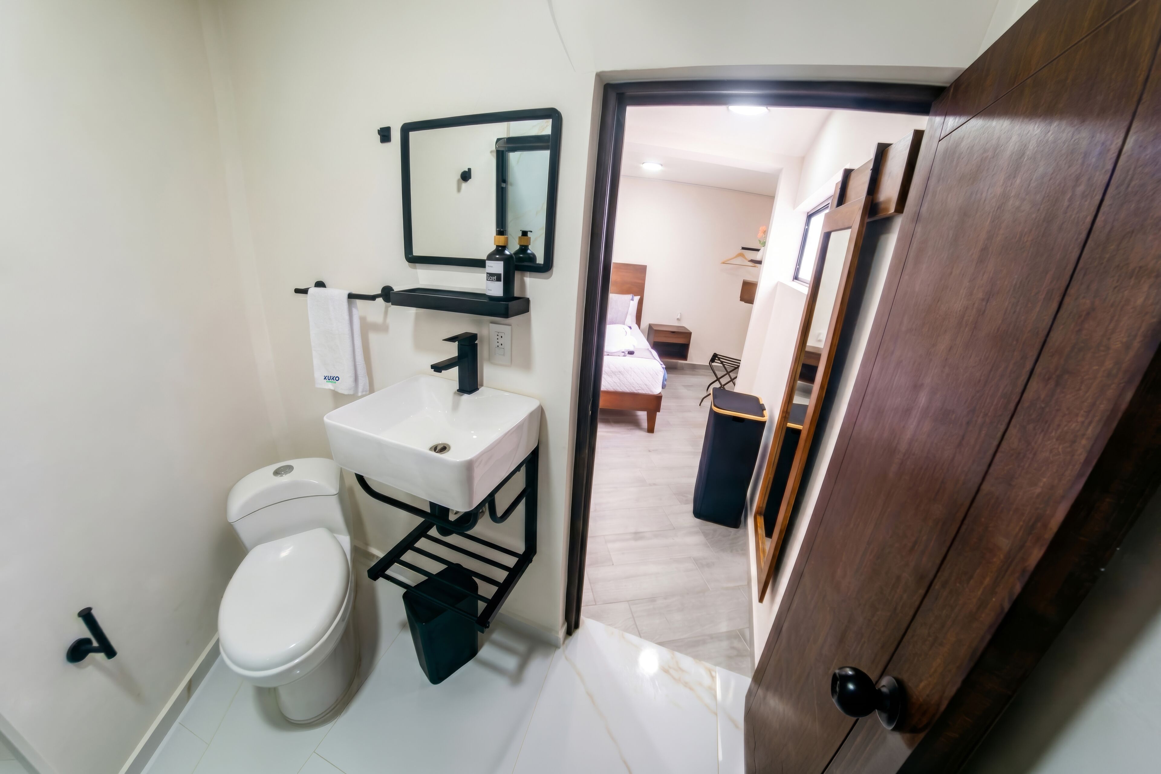 Un bagno con il water, lavandino, specchio e porta asciugamani.