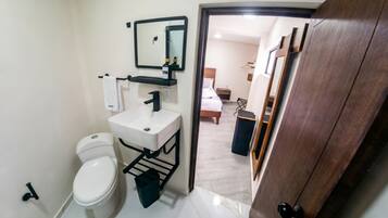 Un bagno con il water, lavandino, specchio e porta asciugamani.