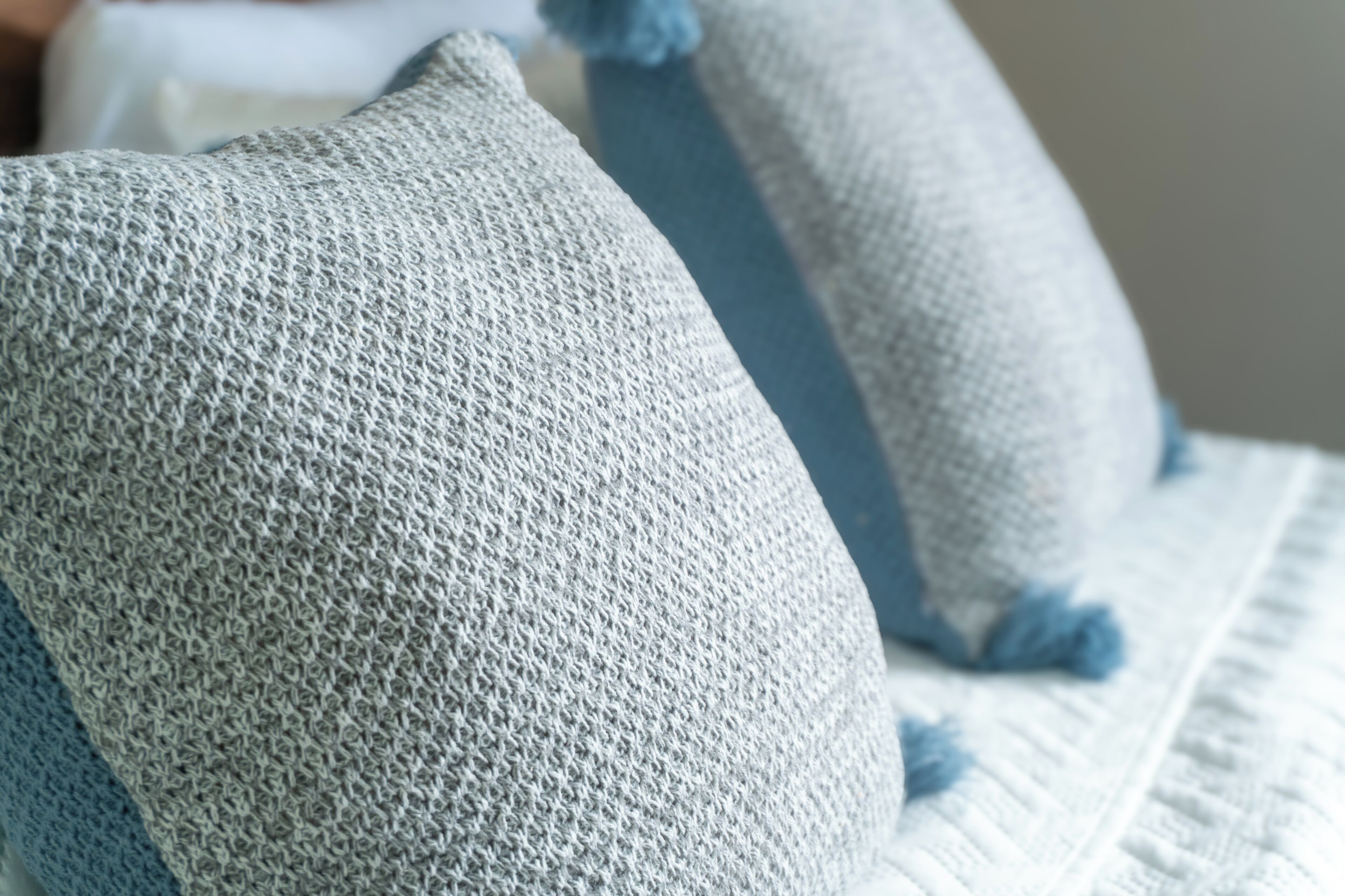 A close-up of a textured fabric, possibly a pillow or cushion, with a visible seam and a tassel.