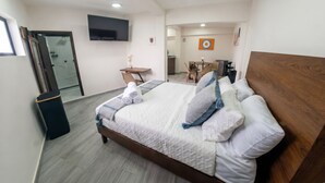 Habitación de hotel con cama, escritorio, silla, televisor y una obra de arte en la pared.