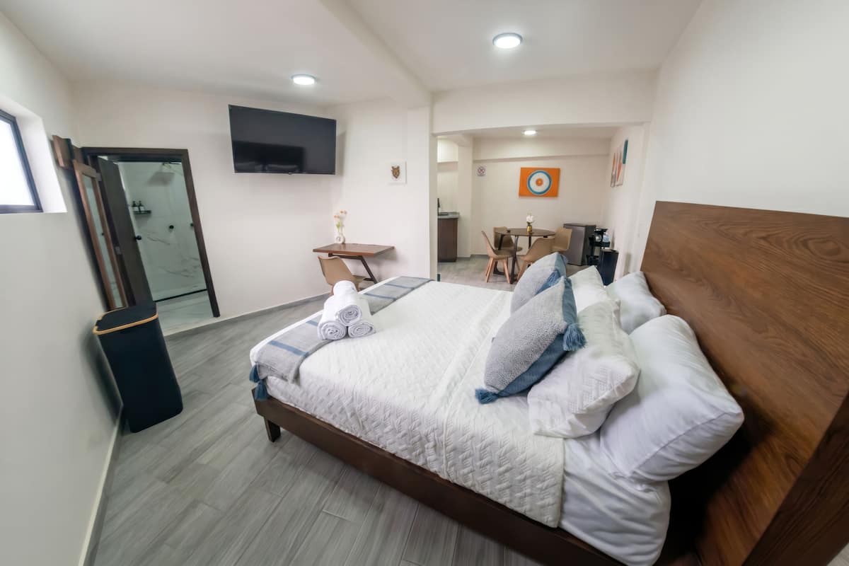Hotellihuone, jossa on sänky, työpöytä, tuoli, televisio ja seinällä oleva taideteos.
