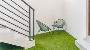 A staircase with metal railings, a green chair, a small table with a potted plant, and a white wall.