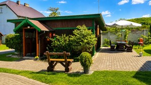 A rustic building with a green roof, a wooden bench, and a paved patio area. - Cottage for 5 People, Wapnica (Międzyzdroje)
