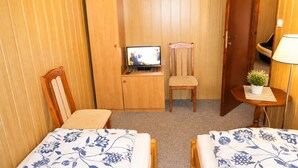 A room with two beds, a wooden wardrobe, a television, a chair, and a small table with a lamp and a plant. - Cottage for 5 People, Wapnica (Międzyzdroje)