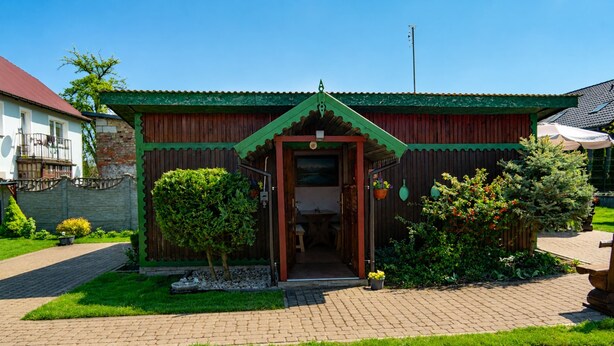 A wooden building with a green roof, a paved entrance, and a small garden area. - Cottage for 5 People, Wapnica (Międzyzdroje)