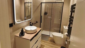Un baño moderno con tocador, espejo, inodoro y ducha.