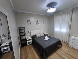 Ein Schlafzimmer mit Bett, Nachttischen, einem Fenster mit Vorhängen und einem Deckenventilator.