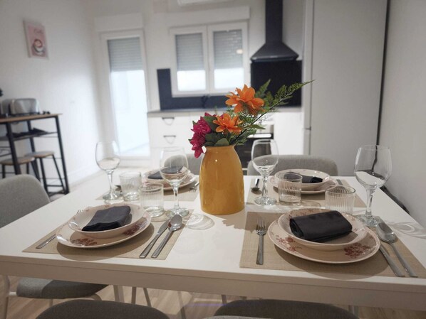 A dining table set with plates, cutlery, and a vase with flowers.