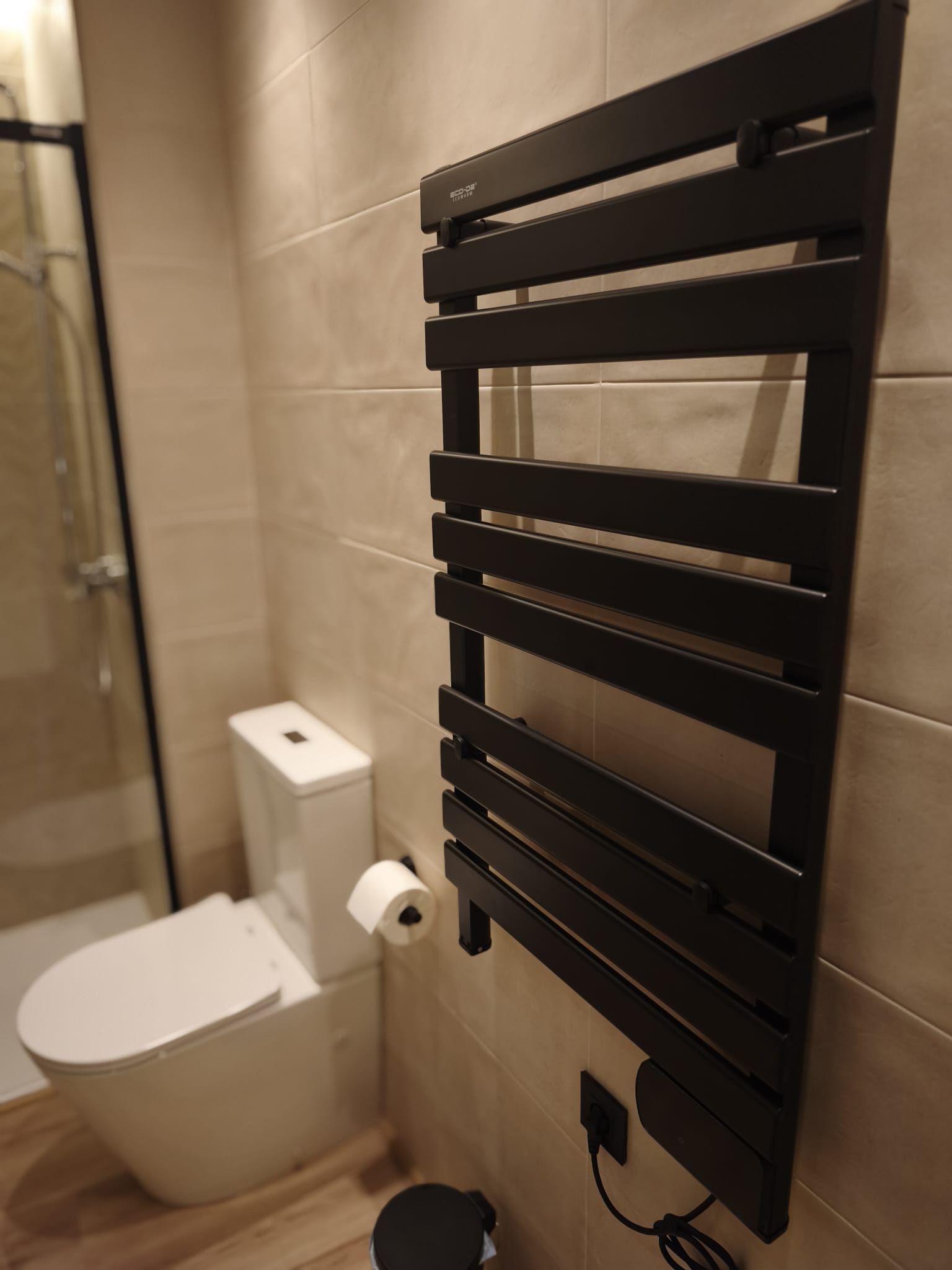 A bathroom with a toilet, a towel rack, and a shower area.