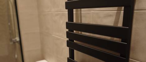 A bathroom with a toilet, a towel rack, and a shower area.