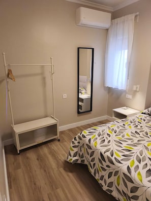A bedroom with a bed, a bedside table, a mirror, an air conditioning unit, and a window with curtains. - Casa Juanito Rute, in the heart of the Sierras Subbeticas, discover Andalusia. (Rute)