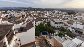 Una zona urbana densamente poblada con edificios blancos, algunos con tejados de tejas rojas, y una vista distante de colinas.