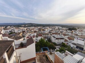 A densely packed urban area with white buildings, some with red-tiled roofs, and a distant view of hills.