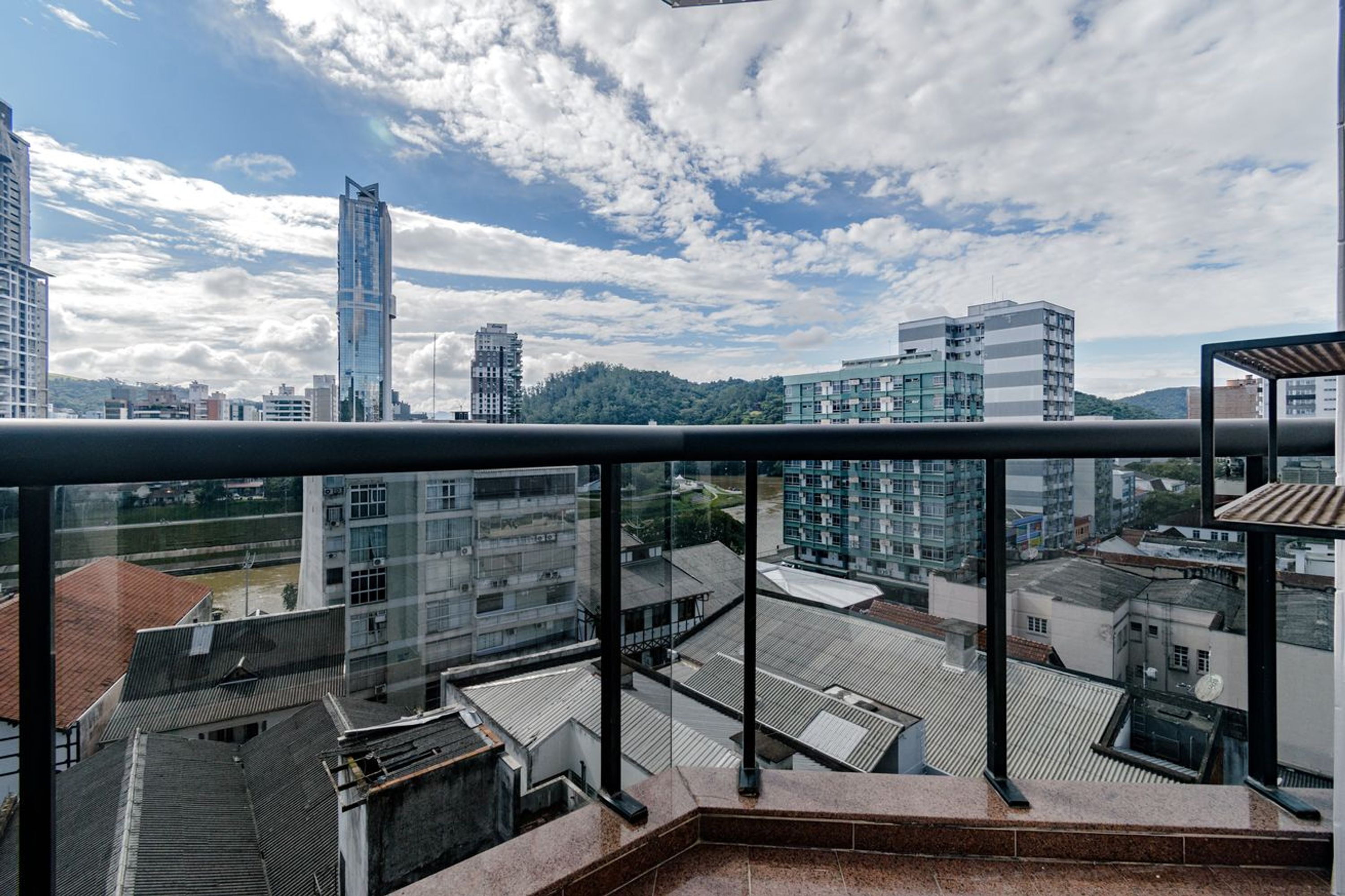 A high-rise building with a glass facade, a clear sky, and a view of other buildings.