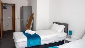Una habitación de hotel con cama, mesita de noche, armario y puerta.