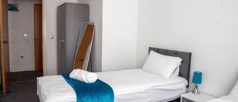 A hotel room with a bed, a nightstand, a wardrobe, and a door.