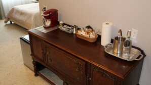 A wooden dresser with drawers, a red appliance, a tray with bottles, and a roll of toilet paper. - Cozy Deluxe Queen Room in Minneapolis Boutique Hotel (Minneapolis)