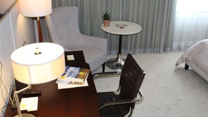 A hotel room with a desk, chair, lamp, small table with a plant, and a bed. - Cozy Deluxe Queen Room in Minneapolis Boutique Hotel (Minneapolis)