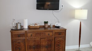 Une commode en bois sur laquelle est fixée une télévision à écran plat, avec une lampe et divers objets décoratifs posés dessus.