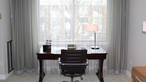 Une pièce comprenant un bureau, une chaise, une lampe et une fenêtre avec des rideaux.