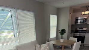 Ein modernes Wohnzimmer mit einer Couch, einem Esstisch und einer Küche im Hintergrund.