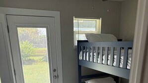 Ein Zimmer mit einem Etagenbett, einer Tür mit Blick nach draußen und einem Deckenventilator.