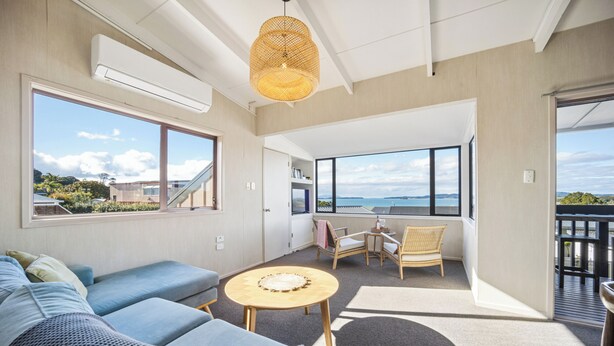 Un intérieur moderne avec un canapé, une table ronde et des chaises, de grandes fenêtres offrant une vue dégagée et un balcon.