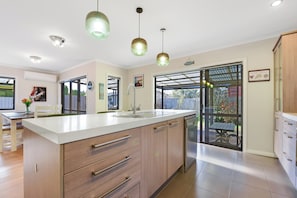 A modern kitchen with a large island, stainless steel appliances, and pendant lighting.