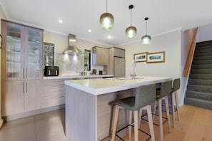 A modern kitchen with a central island, bar stools, and pendant lighting.