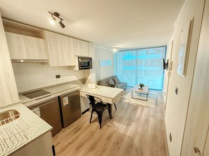 A modern kitchen with a built-in microwave, a dishwasher, and a dining area with a table and chairs. - Moderno depto. en Stgo. cerca del metro (Santiago)