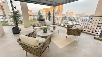A balcony with wicker furniture, a small table, and potted plants.