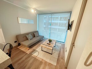 A modern living room with a sofa, a coffee table, and a large window. - Moderno depto. en Stgo. cerca del metro (Santiago)