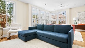 A modern living room with a blue sectional sofa, a white armchair, and a small side table. - The Coral Steps to King and Michelin Restaurants (Charleston)