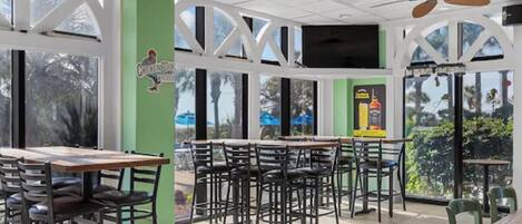 A restaurant with outdoor seating, large windows, and ceiling fans.