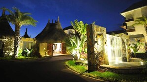 A resort entrance with a thatched-roof building, a waterfall feature, and a well-lit pathway. - Pool View Apartment at 'Domaine dès Alizées Club & Spa' (Grand Baie)