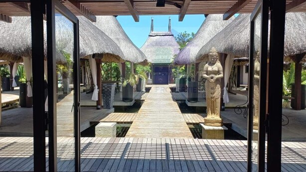 A wooden deck leading to a thatched-roof structure with a statue in the center. - Pool View Apartment at 'Domaine dès Alizées Club & Spa' (Grand Baie)
