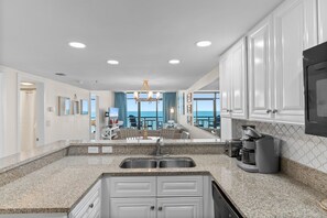 A modern kitchen with granite countertops, white cabinetry, and a built-in coffee maker. - Oceanfront Beach Cove w/ Resort Pools-Wide Balcony (North Myrtle Beach)