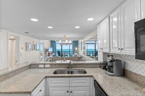 A modern kitchen with granite countertops, stainless steel appliances, and a view to the outside. - Oceanfront beach cove w/ Resort pools-Wide balcony (North Myrtle Beach)