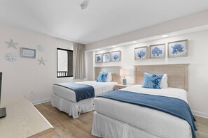 Ein Hotelzimmer mit zwei Betten, einem Schreibtisch und einem Fenster mit Vorhängen.