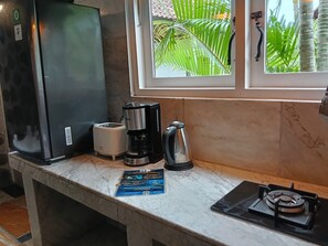 Une cuisine équipée d’un réfrigérateur, d’une machine à café, d’une bouilloire et d’une cuisinière à gaz.