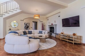 Un salon spacieux avec un canapé incurvé, une table basse et une cheminée.